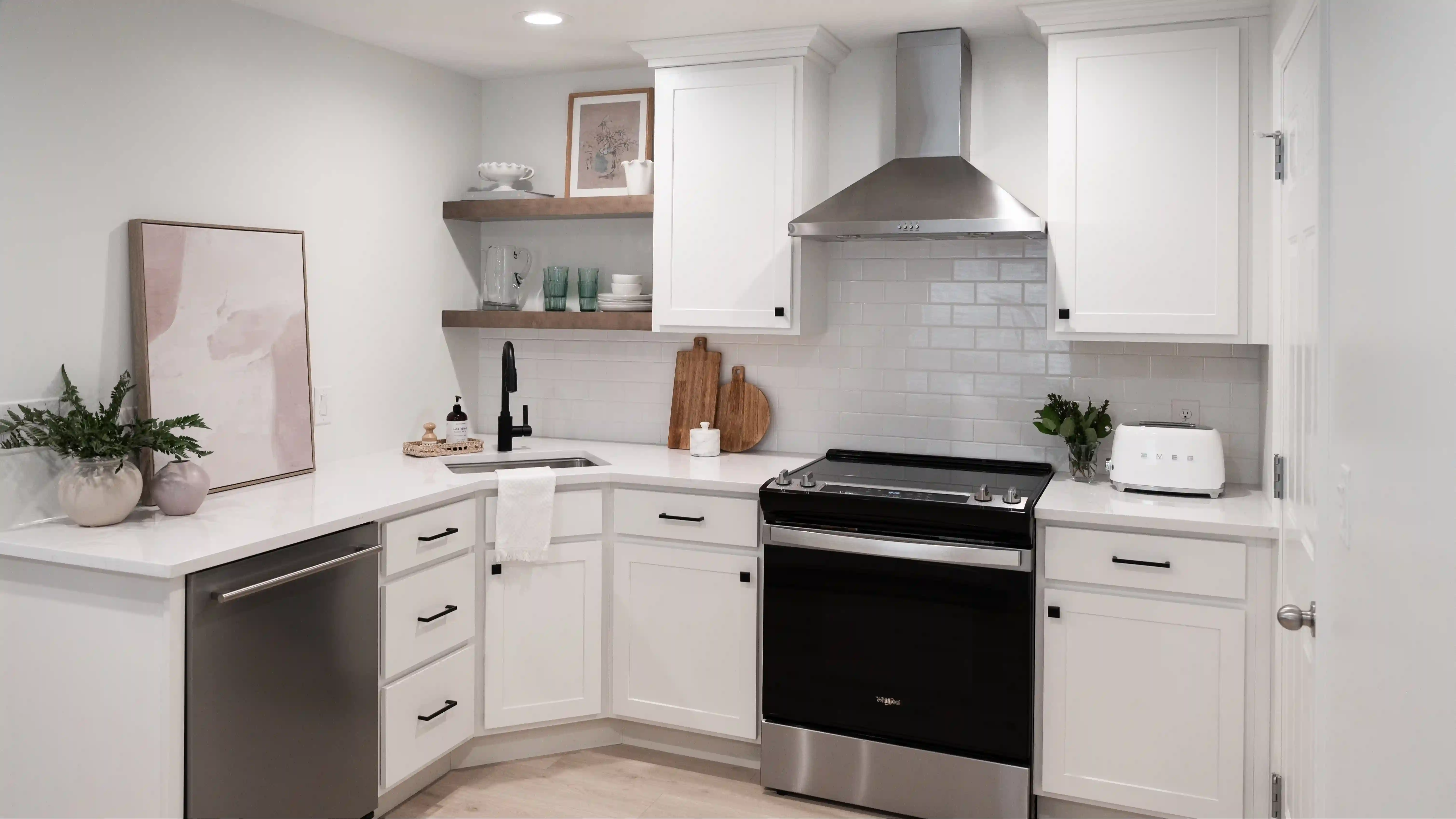 A small kitchen with white subway tile backsplash above white quartz countertops over white cabinetry. This small kitchen was designed strategically for the small room it had to be built within. 