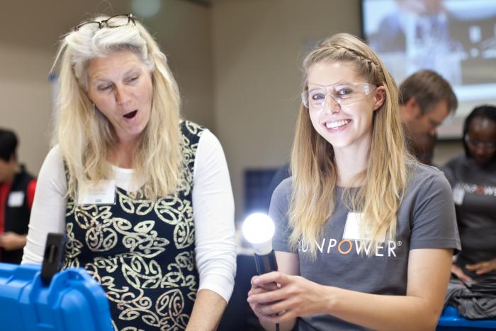 A student and teacher work together to build a solar-powered portable light in a suitcase.