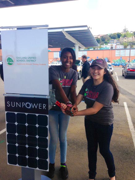 Students Ronye Cooper and Sandra Vivian-Calderon excitedly flip the big switch at the OUSD solar dedication ceremony. (Photo by Renee Solari.)