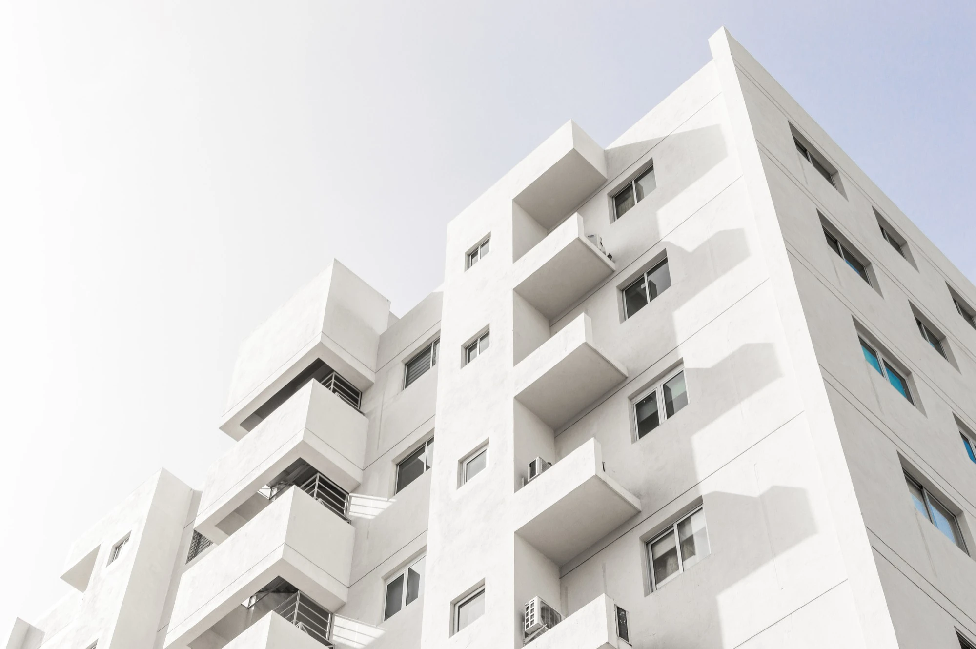 Photo d'un immeuble moderne blanc, sur fond très clair.