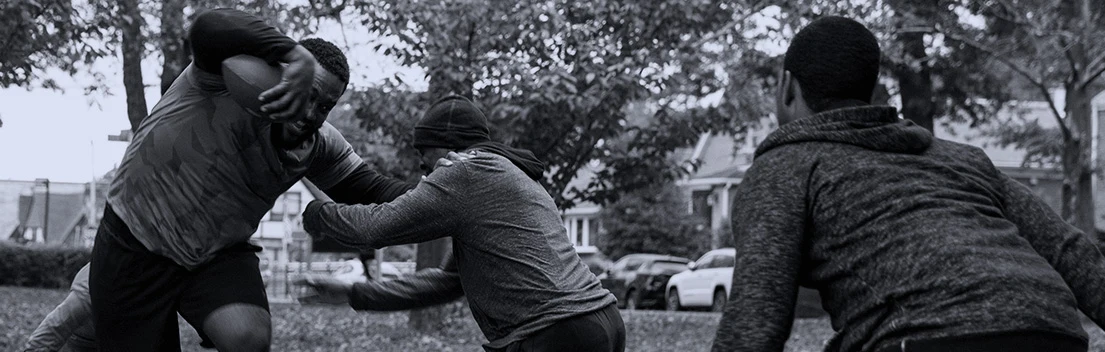 A black and white image of three adults playing football