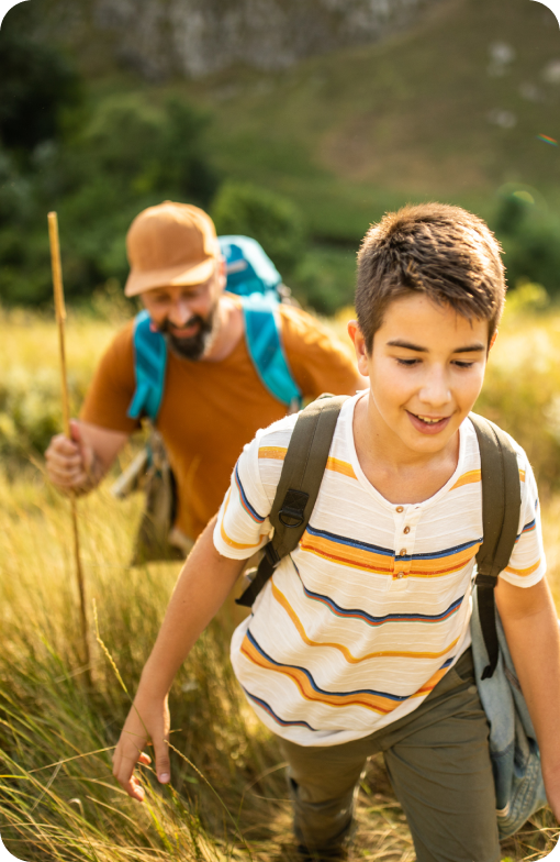 A man and a boy hiking outdoors, both carrying backpacks, suggesting preparedness and adventure.