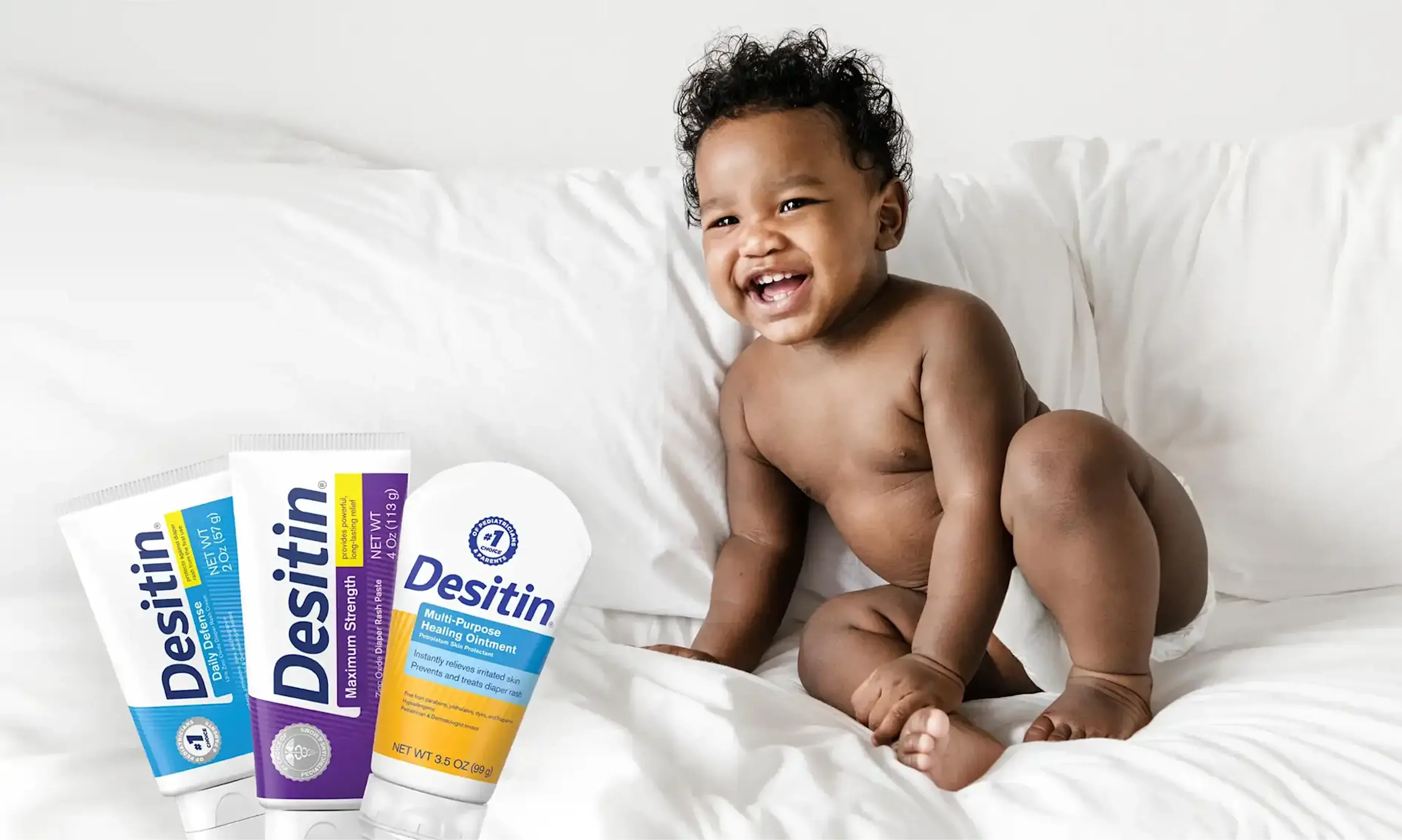 Desitin® Product Collection banner, a baby radiantly smiling when sitting on the comforter
