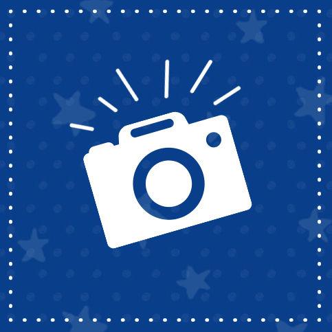 Icon of a white camera with rays on a blue background with star patterns.