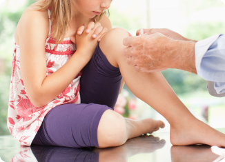 A child receiving treatment for a minor wound on the knee.