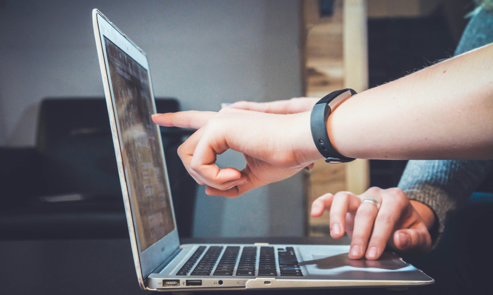 Two people pointing on a computer