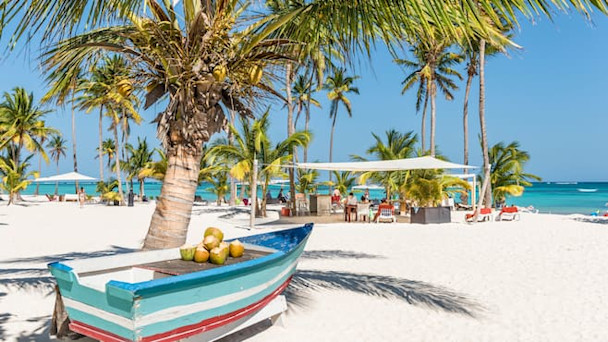 Strand i Punta Cana med en båt med kokosnötter som ligger på stranden