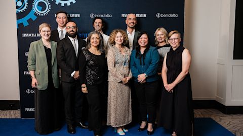 A group of City of Sydney employees pose together on a blue carpet in front of a branded backdrop.