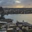 Panoramic view of sydney skyline featuring the harbour bridge and opera house with a stormy sky in the background.