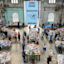 People browse tables of books at the Sydney Writers’ Festival bookshop inside a large industrial-style hall with high windows.