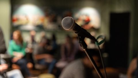 Microphone in focus with an audience seated in the background.