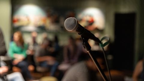 Microphone in focus with an audience seated in the background.