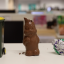 Partially eaten chocolate bunny next to a miniature city of sydney trash bin and crumpled foil wrapper.
