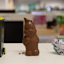 Partially eaten chocolate bunny next to a miniature city of sydney trash bin and crumpled foil wrapper.