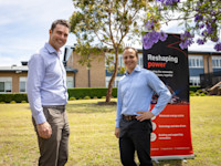 2 young men standing on a lawn outside a BapistCare aged care facility