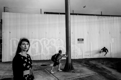 Black and white photo of woman next to wall covered in graffiti art