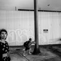 Black and white photo of woman next to wall covered in graffiti art