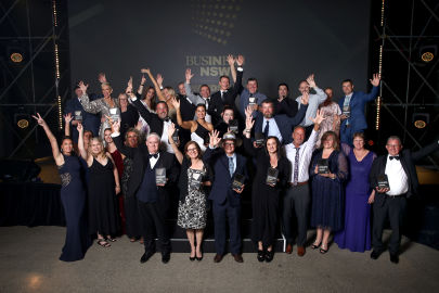 Group of people posing with awards at a business event.