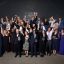 Group of people posing with awards at a business event.