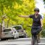 A woman signals to turn while on a bike in a suburban street in Syndey