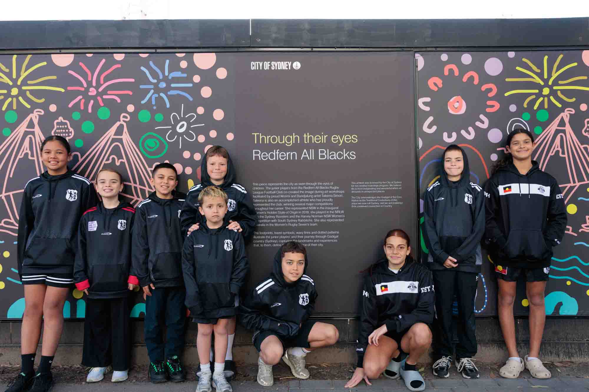 Members of the Redfern All Blacks with their artwork on Link Road in Zetland. Image: Phoebe Pratt / City of Sydney 