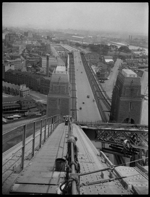 This photo, taken from the top chord of the Sydney Harbour Bridge during construction in 1932, is fascinating. Tram lines run along the left side of the bridge, with train lines on the right. Some of the present-day historic buildings of The Rocks and the Walsh Bay wharves are clearly visible. In the background, smoke pours from the stacks of factories in Pyrmont. Photo: Percy James Bryant / City of Sydney Archives A-01142115