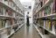 A man reads a book while standing in between the shelves at Kings Cross library