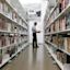 A man reads a book while standing in between the shelves at Kings Cross library
