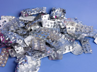 Pile of empty plastic and foil blister packs against a blue background. 