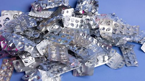 Pile of empty plastic and foil blister packs against a blue background.