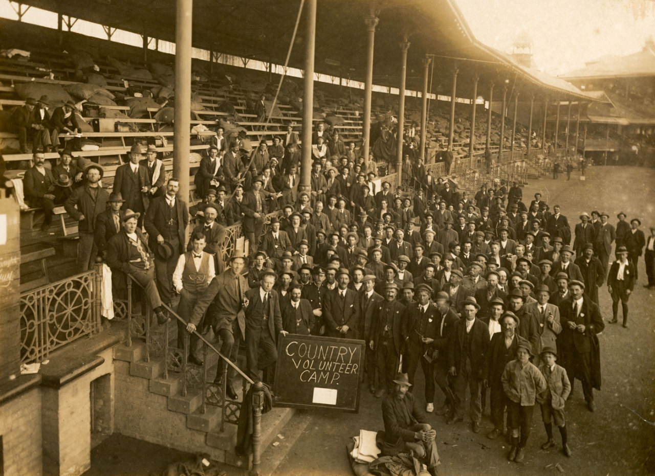 A group of men and boys from the ‘Country Volunteer Camp’ gathered in front of the Brewongle Stand at the Sydney Cricket Ground. Image: Australian War Memorial P09919.001