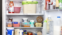 Open refrigerator showing various food items, including containers, a pineapple, eggs, milk, sauces, jars, spreads, and a large tub on the top shelf.