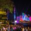 Crowd of people at a nighttime outdoor event with colorful light projections on the sydney opera house.