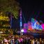 Crowd of people at a nighttime outdoor event with colorful light projections on the sydney opera house.