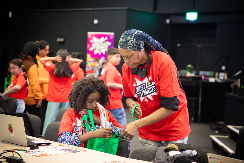 A mentor and a young girl look at a bag of prizes at an event.