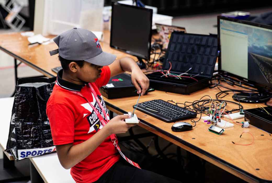 A young boy adds wires to a tech project