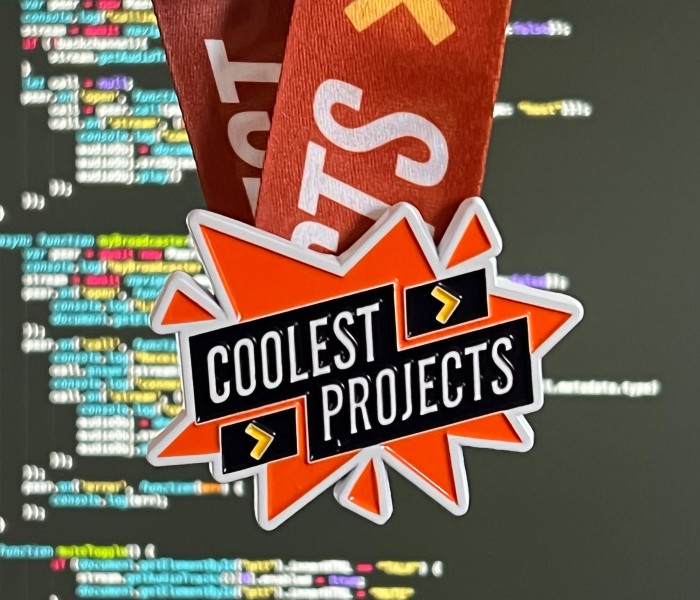 A Coolest Projects medal hangs from a ribbon in front of a screen of computer code.