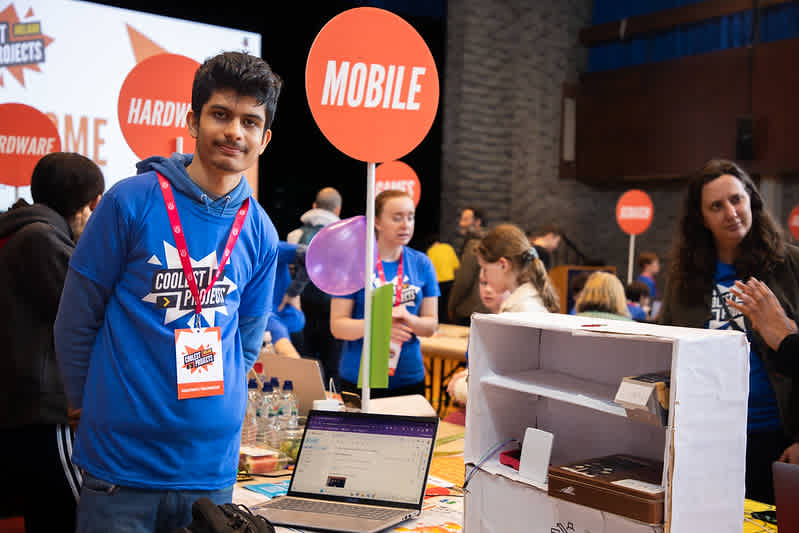 A young man displays his coding project at an event.