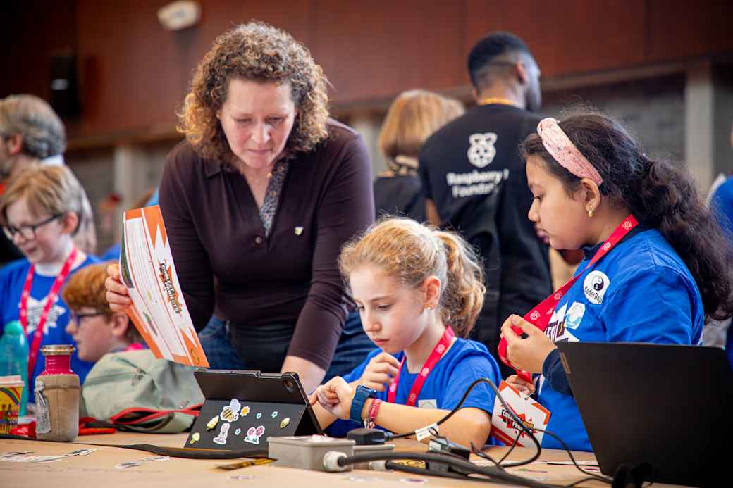 Two young participants demonstrate their work to a judge at a Coolest Project event