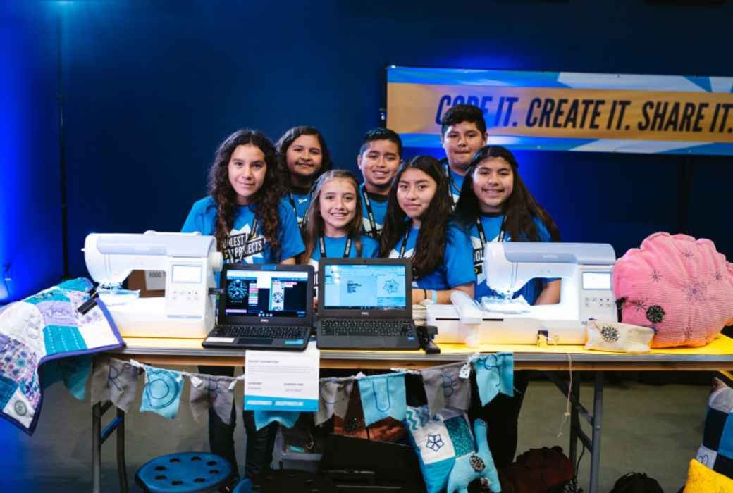 A group of young creators around two computers and two sewing machines