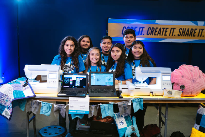 A group of young creators around two computers and two sewing machines