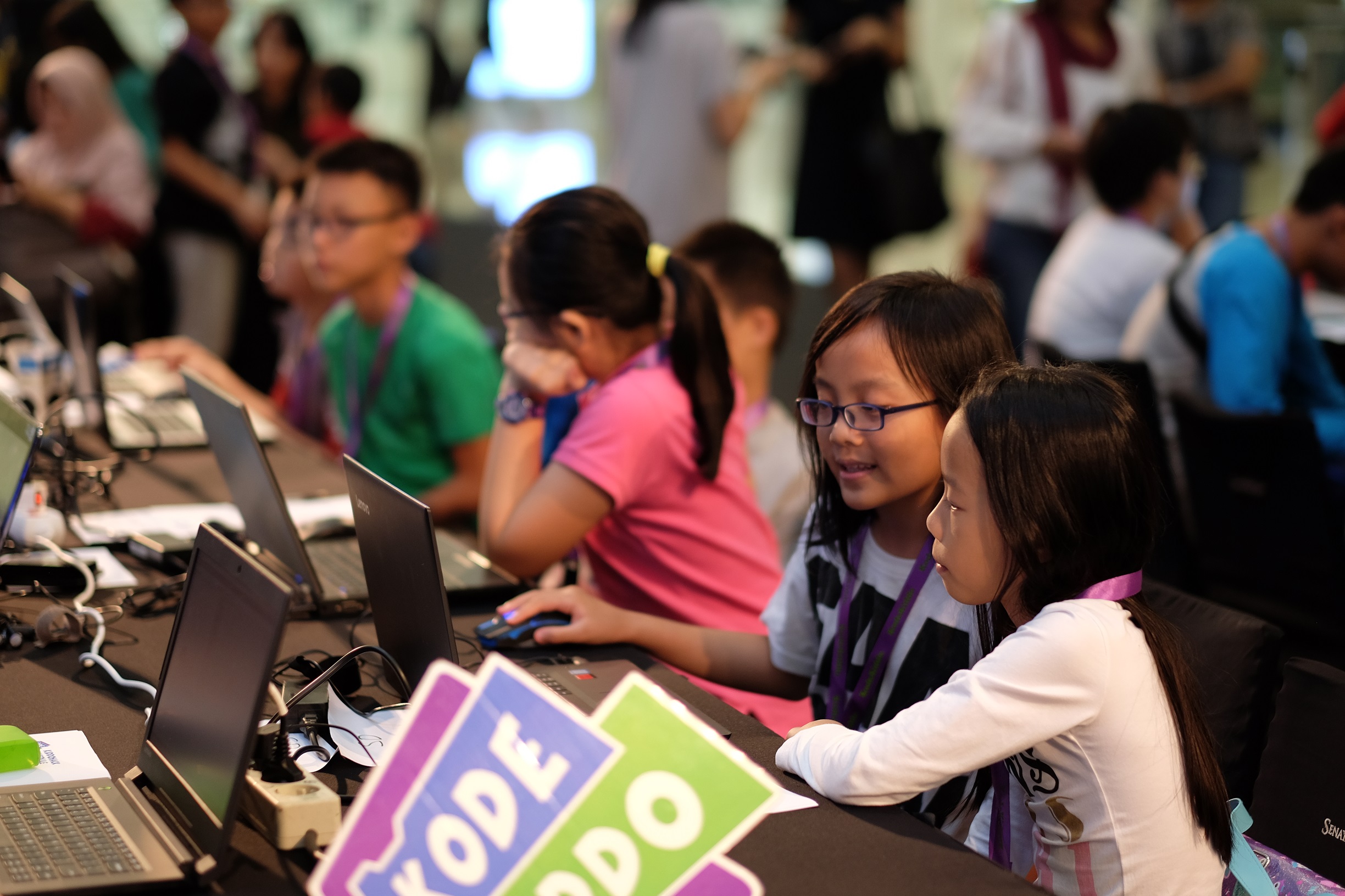 Young people look at laptops at an event.