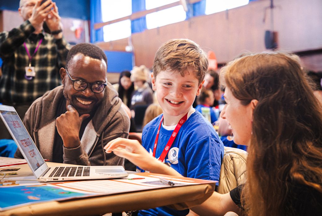 A young participant talks to two judges at an event.