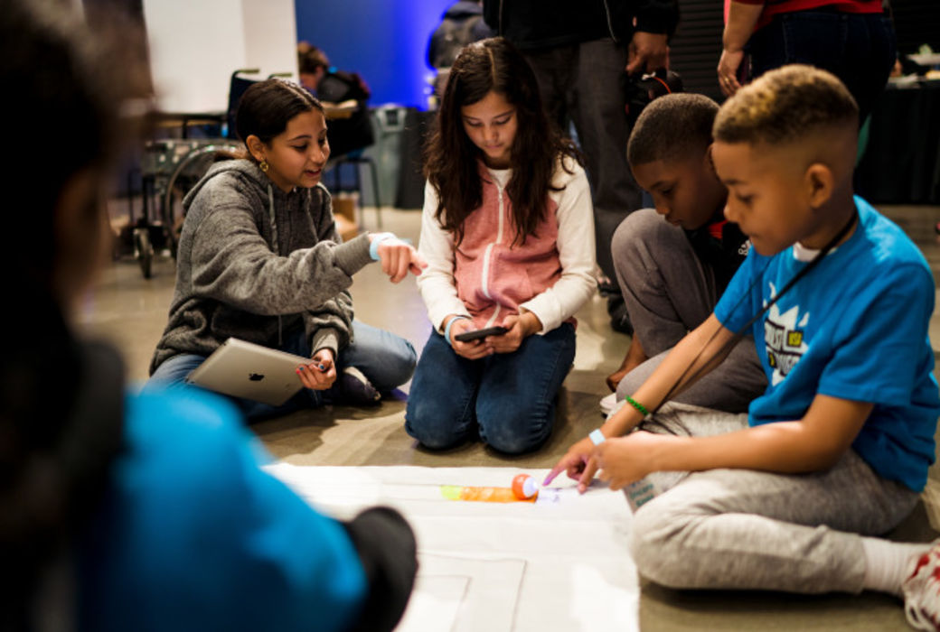 Two girls and two boys work on a technology project together.