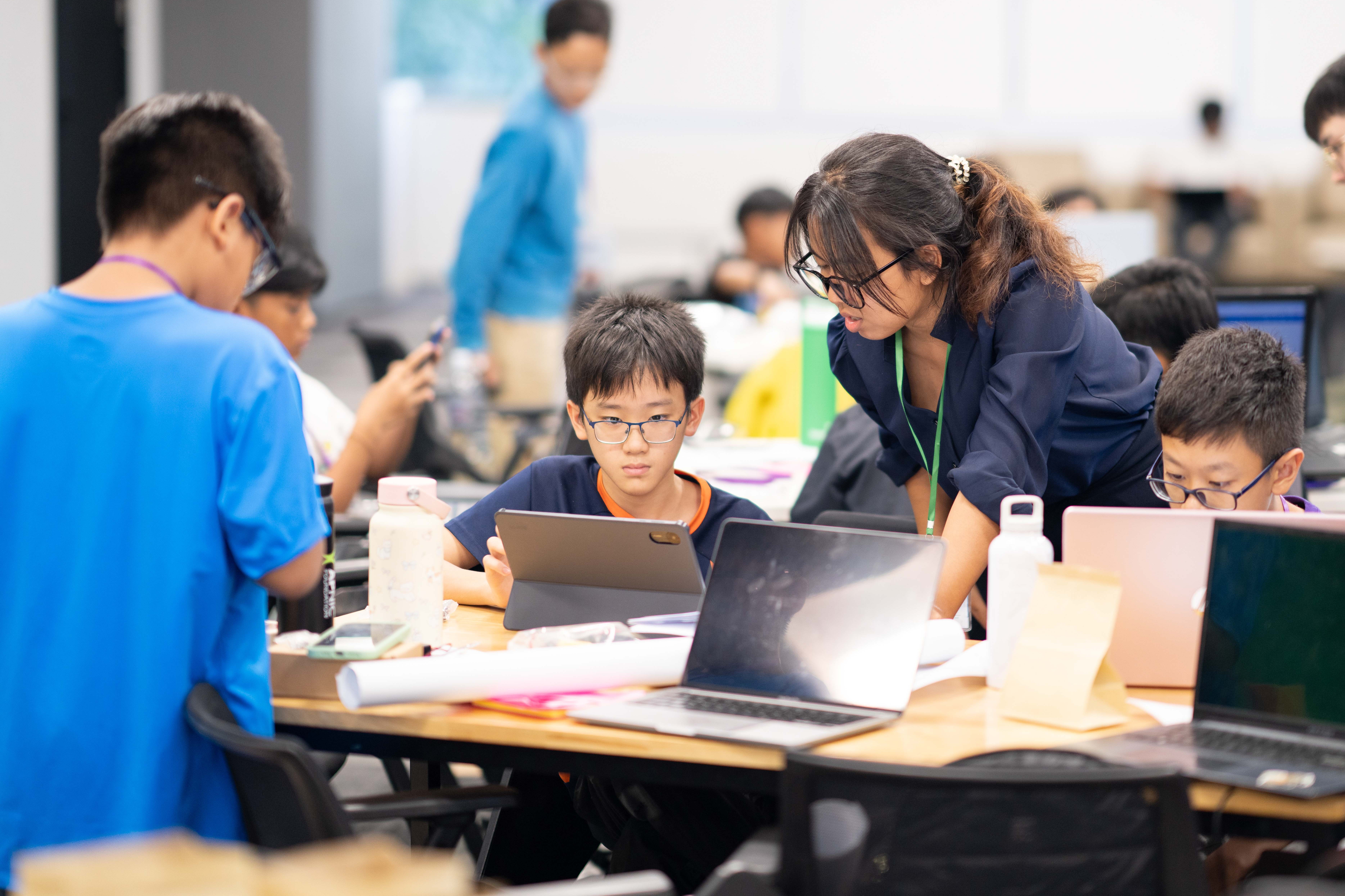 Young people at a computing event look at laptops.