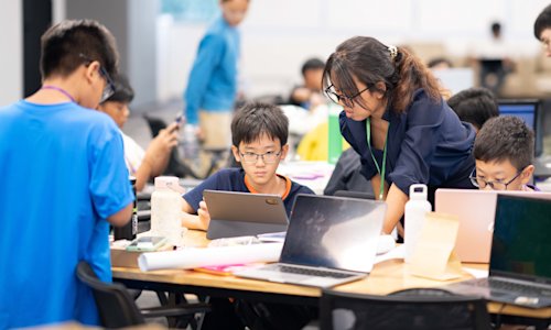 Young people at a computing event look at laptops.