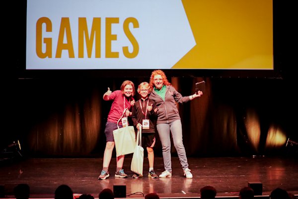 Two young boys collect awards on a stage, from a judge.