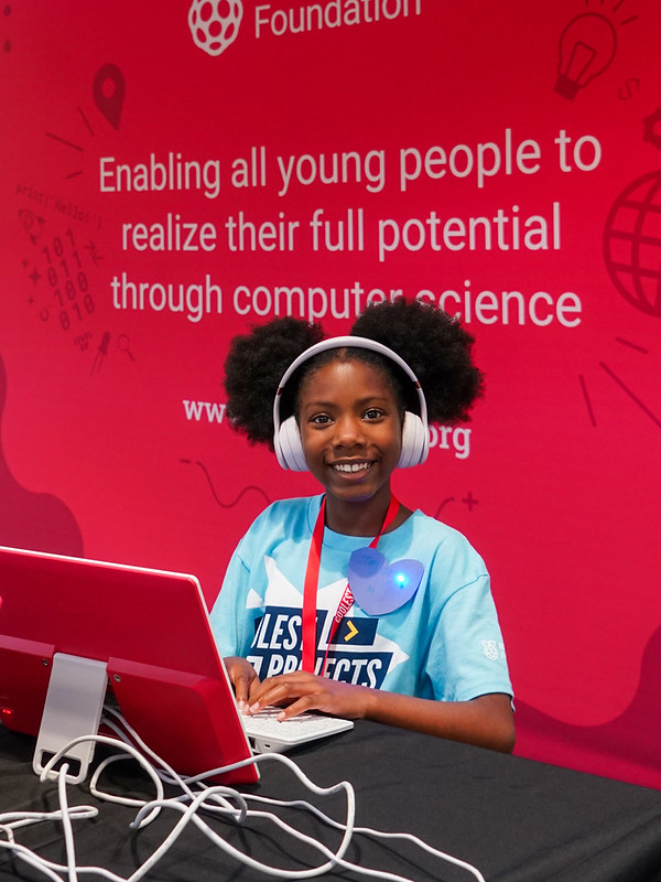 A young girl wearing headphones sits at a computer.