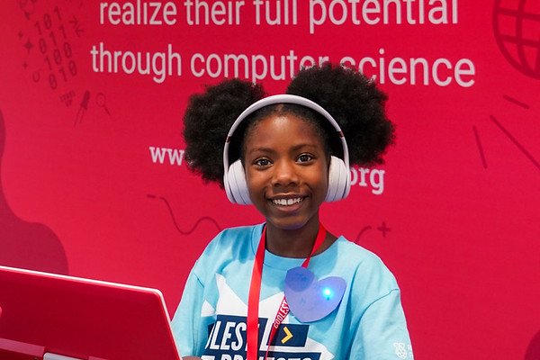A young girl wearing headphones sits at a computer.