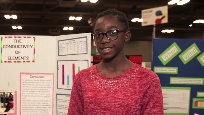 A young girl in front of her science project.